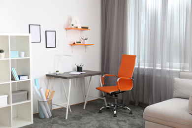 Photo of Stylish room interior with comfortable workplace near window. Design idea