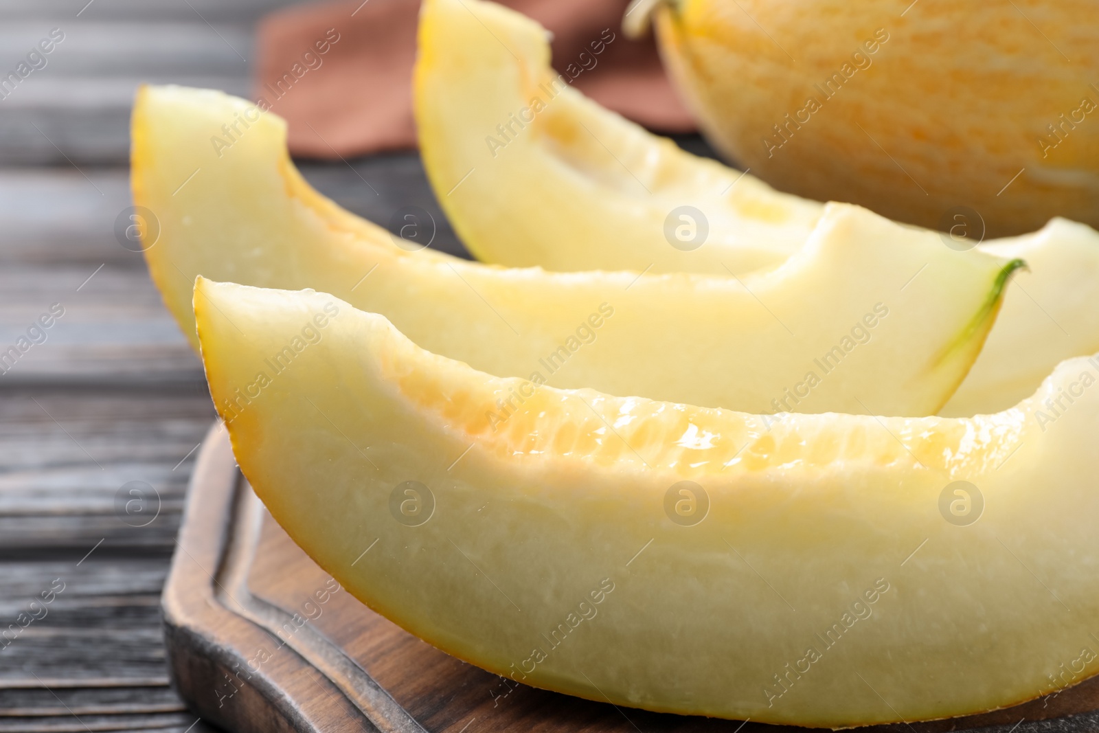 Photo of Pieces of delicious honeydew melon on wooden board, closeup