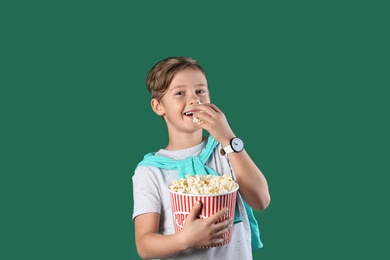 Photo of Cute boy with popcorn bucket on color background