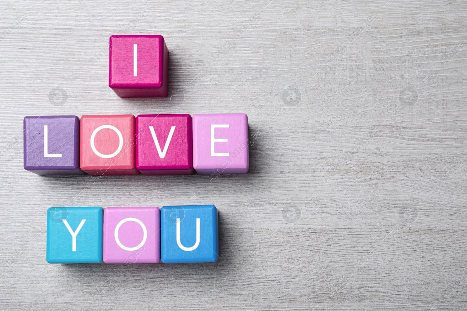 Photo of Phrase I love You made of color cubes on wooden background, flat lay. Space for text