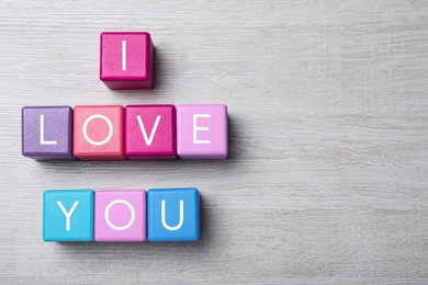 Photo of Phrase I love You made of color cubes on wooden background, flat lay. Space for text