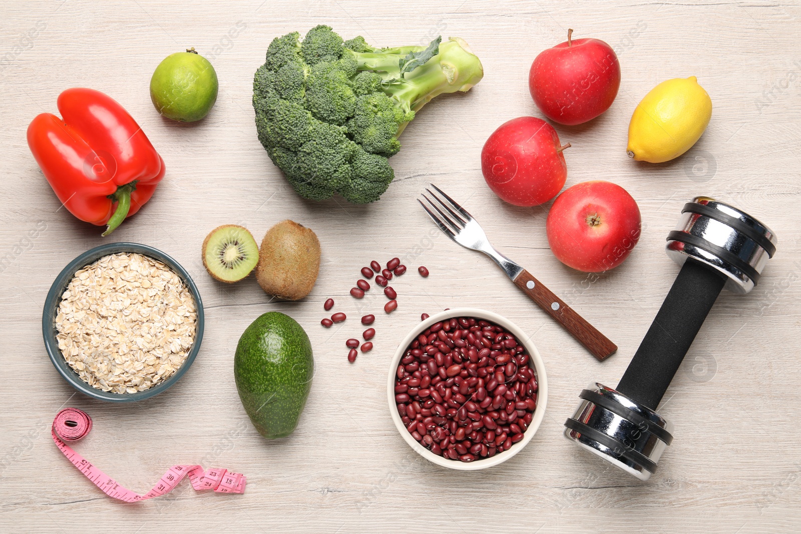 Photo of Healthy diet. Different products, dumbbell and measuring tape on light wooden table, flat lay