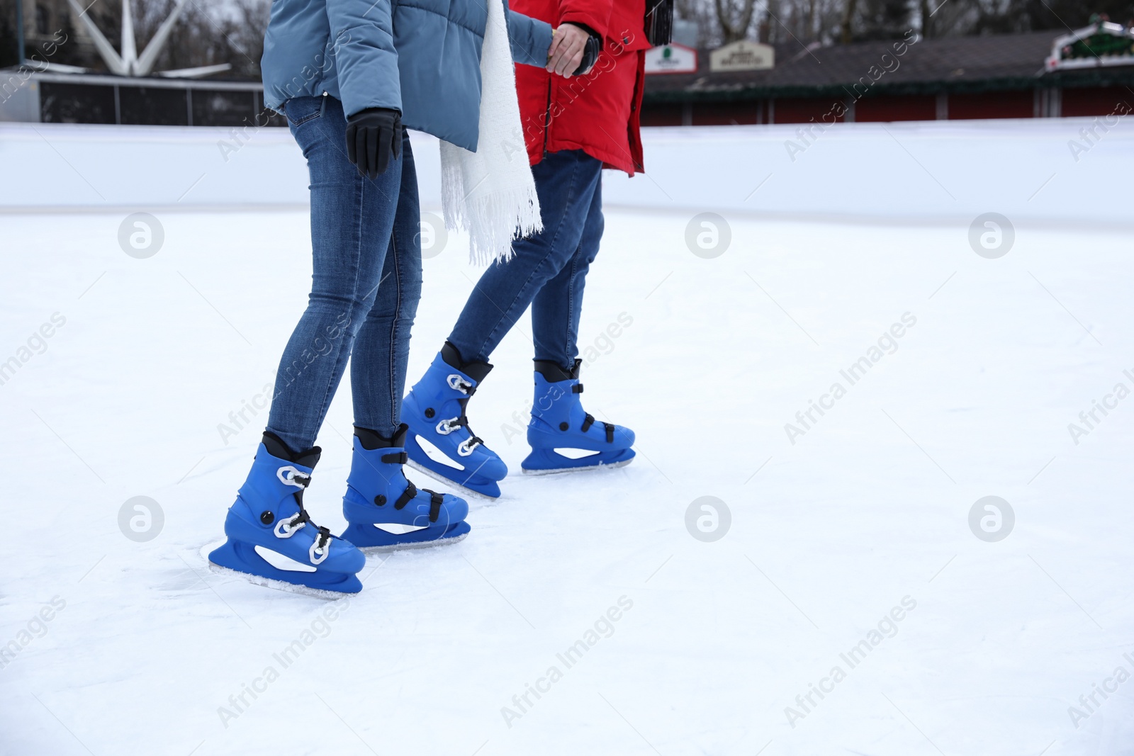 Image of Couple skating along ice rink outdoors, closeup