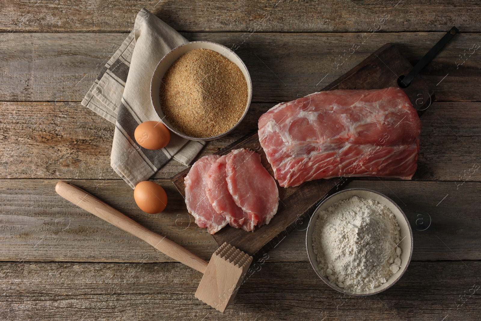 Photo of Different ingredients for cooking schnitzel on wooden table, flat lay