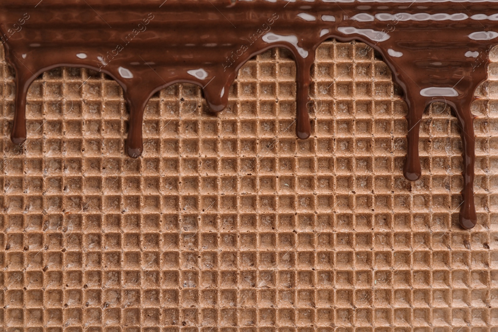 Photo of Hot dark chocolate on wafer, closeup. Crispy food