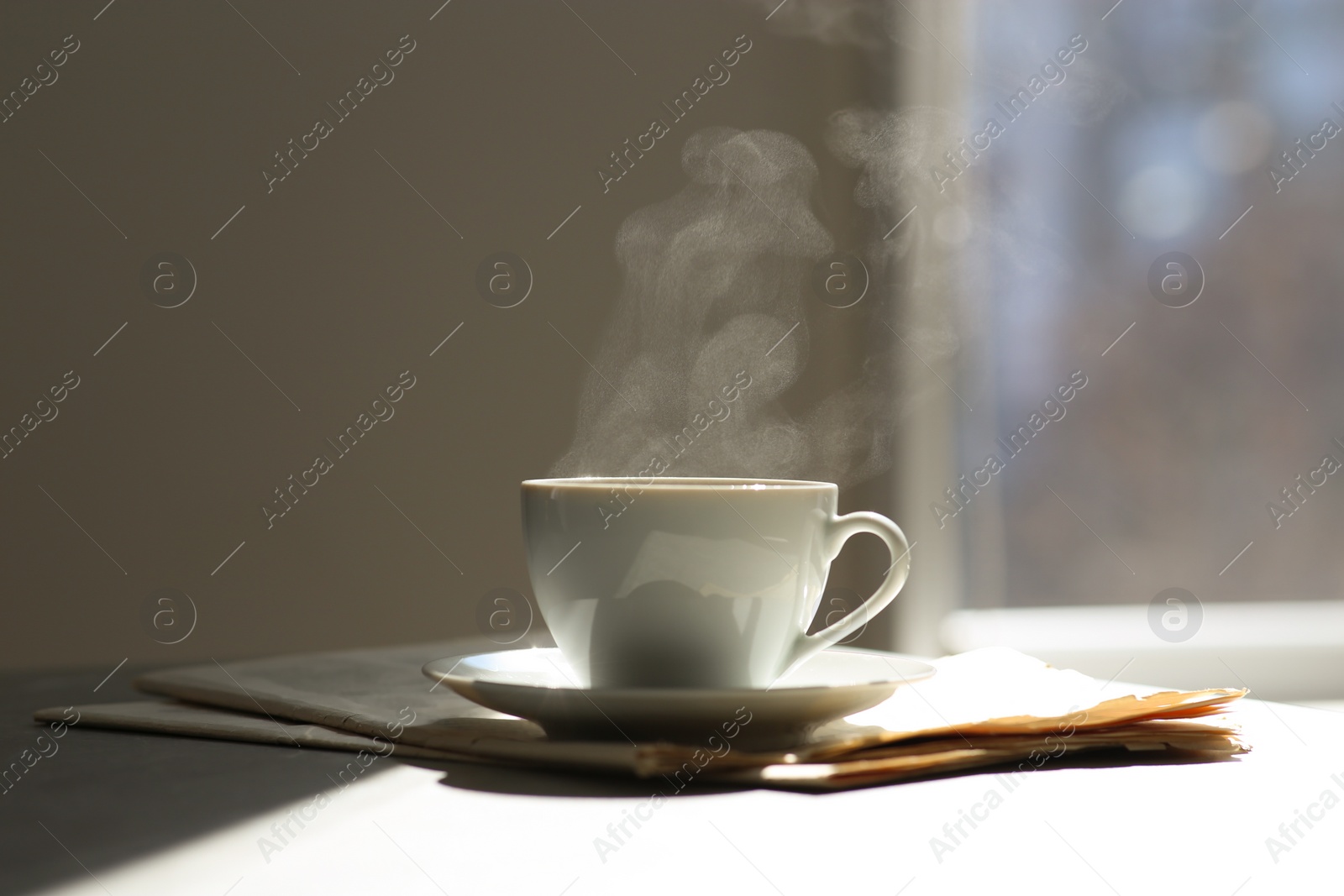 Photo of Delicious coffee and newspaper on sunlit table. Good morning