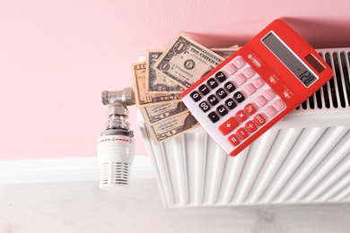 Heating radiator with calculator and money on color wall