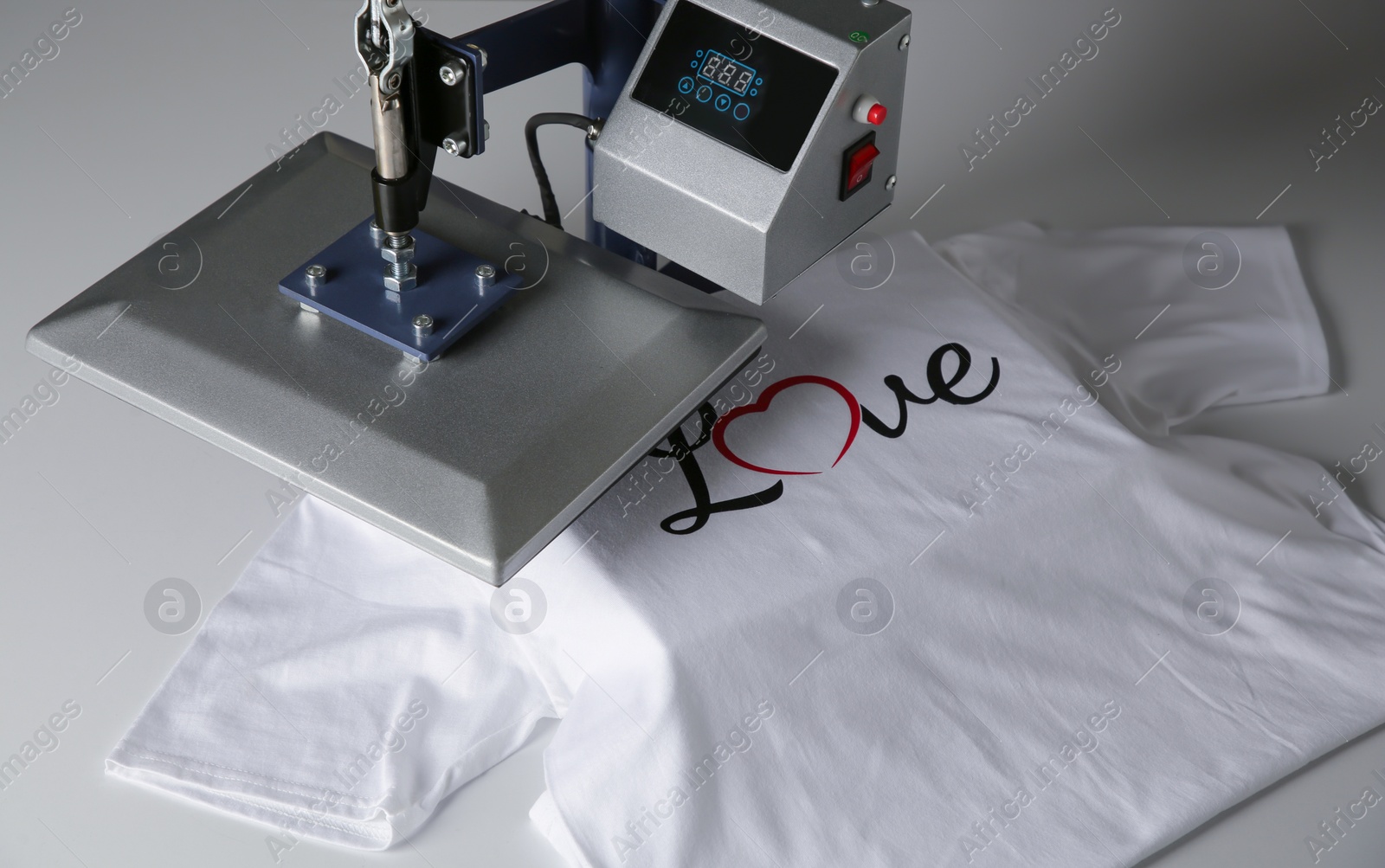 Photo of Printing logo. Heat press with t-shirt on white table