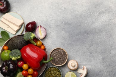 Photo of Different vegetables on grey table, flat lay and space for text. Vegan diet