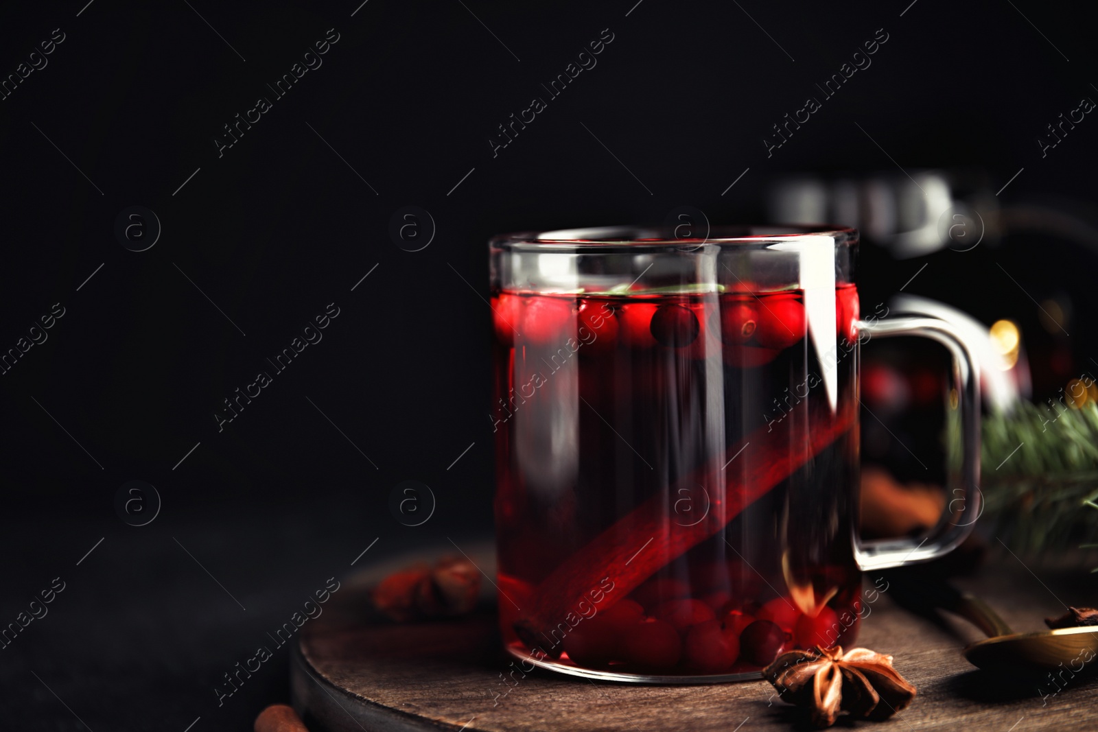 Photo of Tasty hot cranberry tea with anise and cinnamon on black table. Space for text