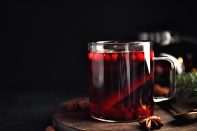 Photo of Tasty hot cranberry tea with anise and cinnamon on black table. Space for text