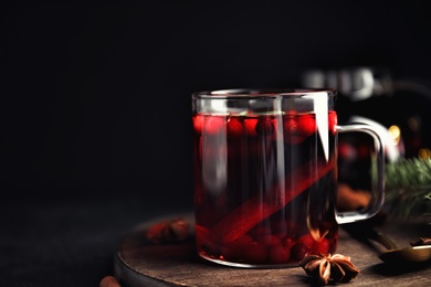 Tasty hot cranberry tea with anise and cinnamon on black table. Space for text