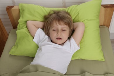 Photo of Little boy snoring while sleeping in bed at home, above view