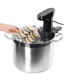 Photo of Woman putting vacuum packed eggplant into pot with sous vide cooker on white background, closeup. Thermal immersion circulator