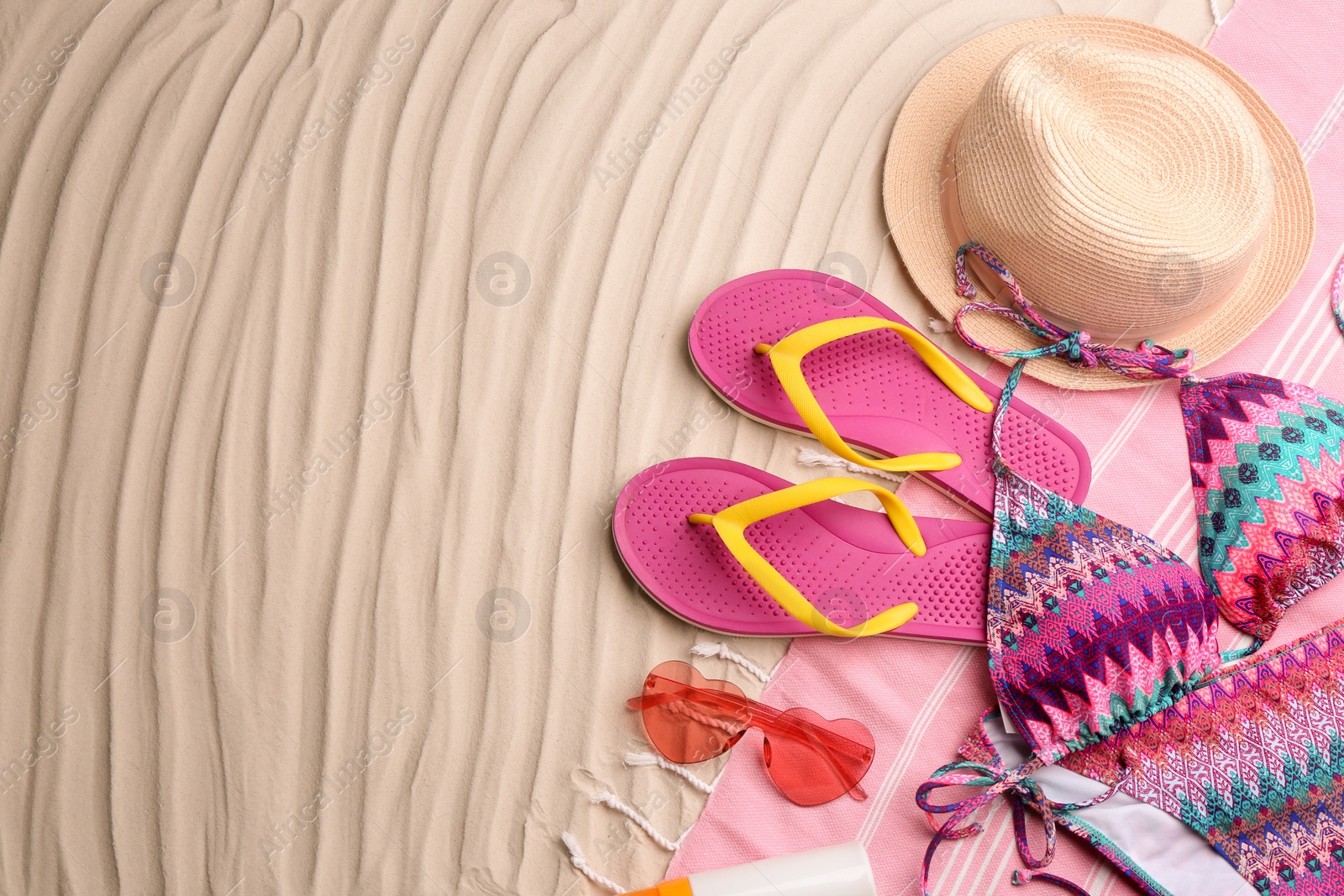 Photo of Different beach accessories on sand, flat lay. Space for text