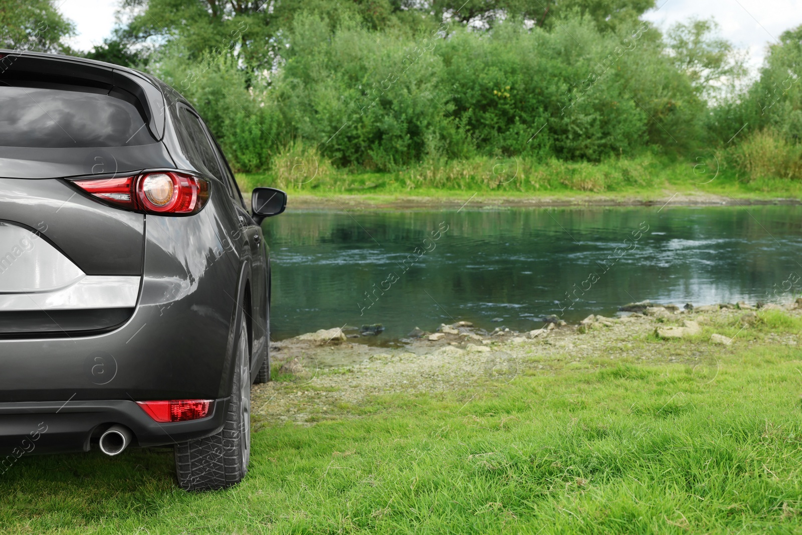 Photo of New black modern car near river, closeup of taillight. Space for text