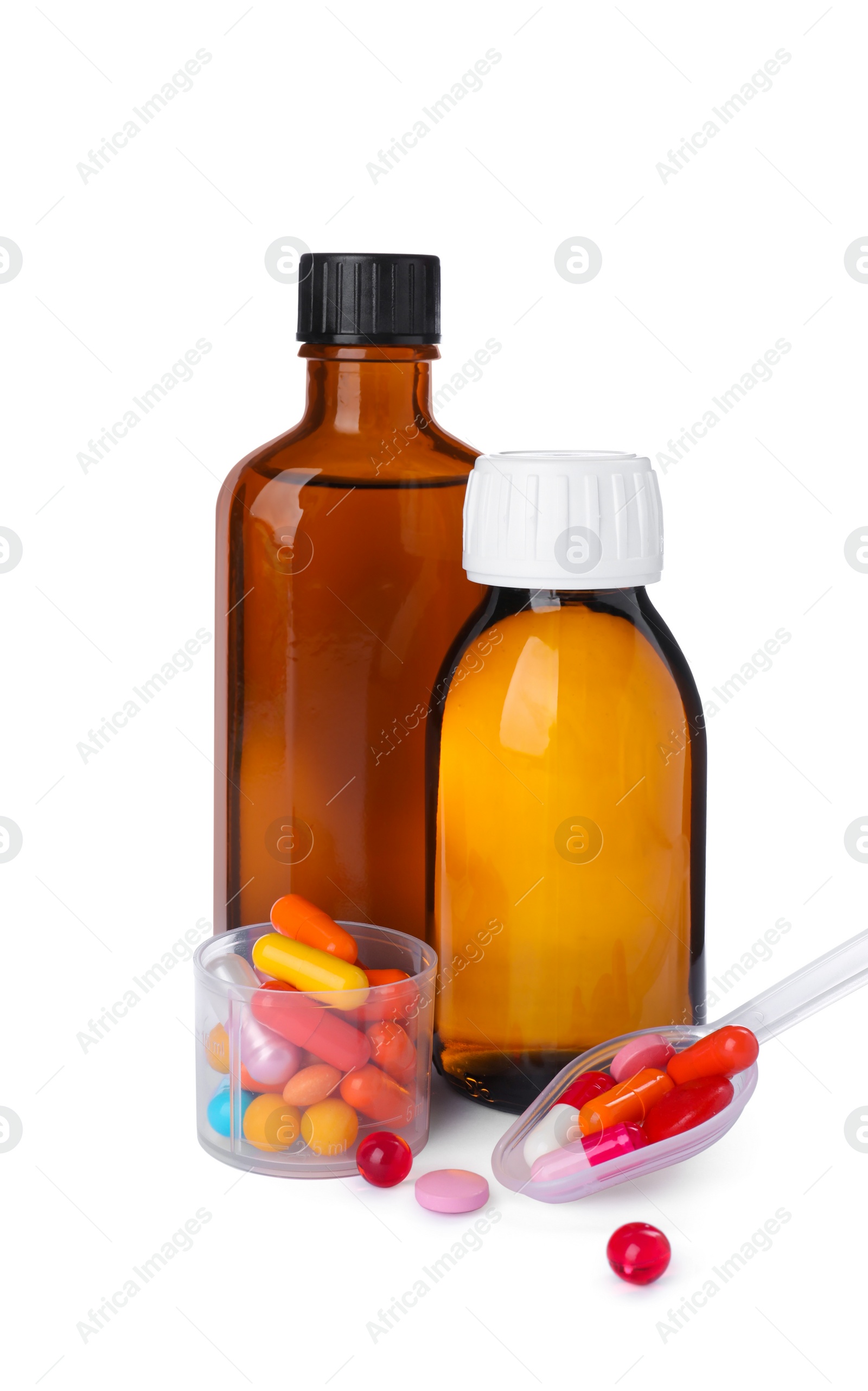 Photo of Bottles of syrups, measuring cup, plastic spoon with pills on white background. Cough and cold medicine