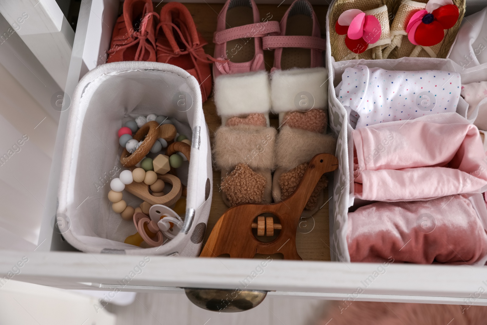 Photo of Modern open chest of drawers with baby clothes and accessories, top view