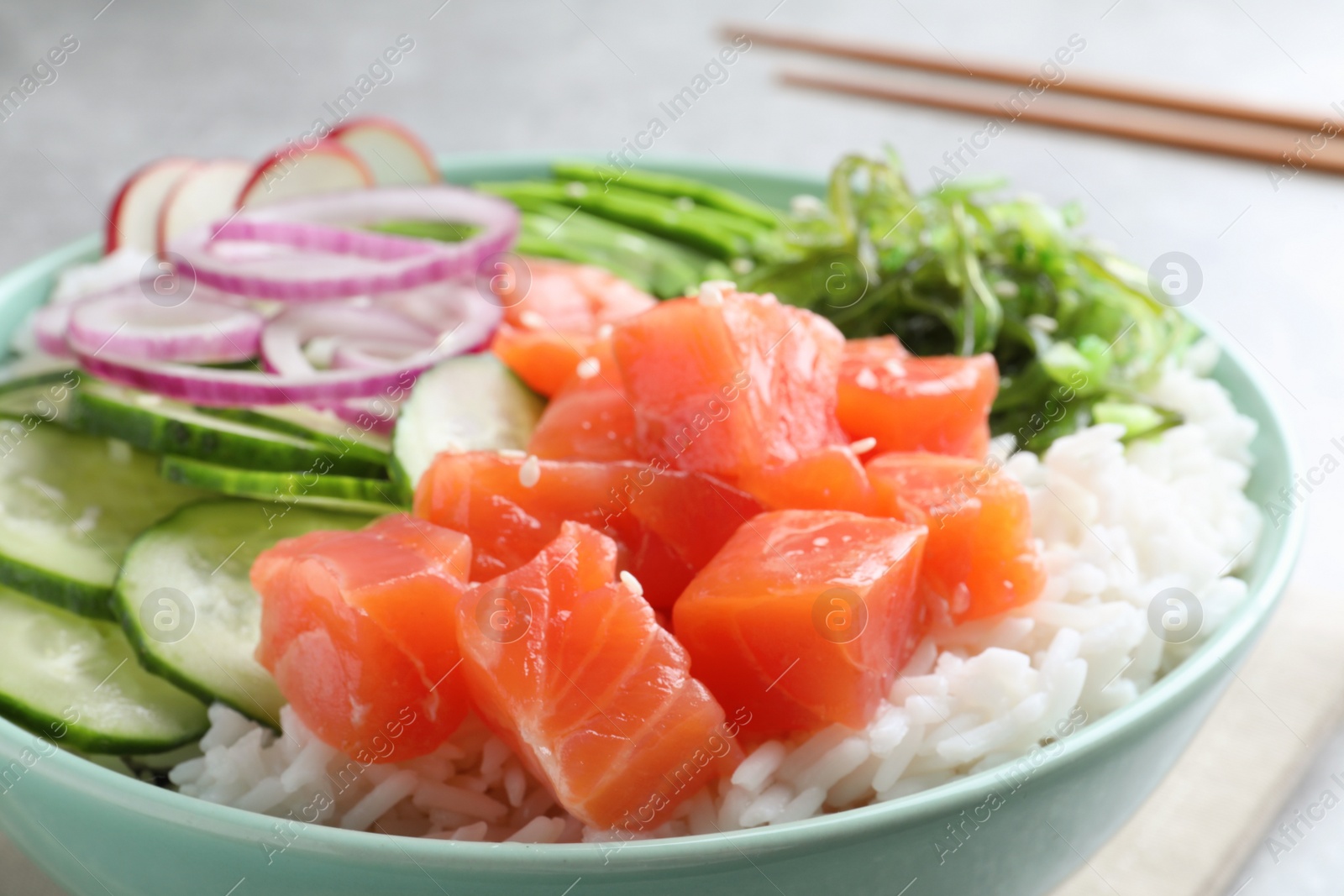 Photo of Delicious poke bowl with salmon, rice and vegetables on table, closeup