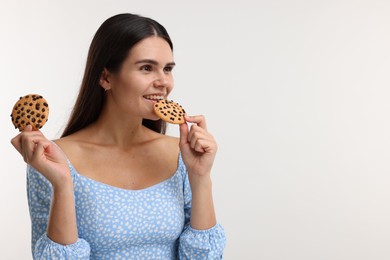 Photo of Young woman with chocolate chip cookies on white background, space for text