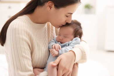 Mother kissing her sleeping newborn baby at home