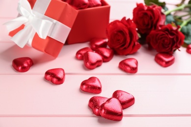 Photo of Heart shaped chocolate candies on pink wooden table