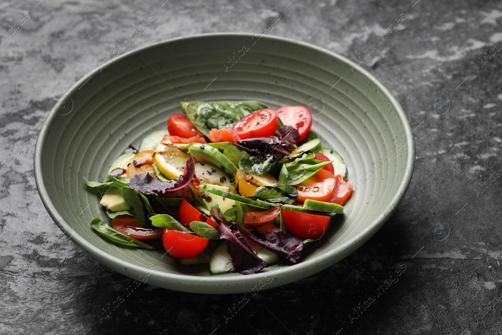 Photo of Delicious vegetable salad on black textured table