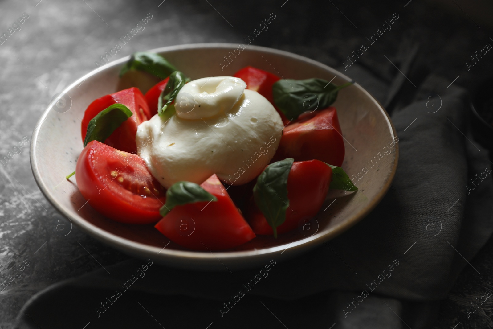 Photo of Delicious burrata cheese with tomatoes and basil on grey table, closeup