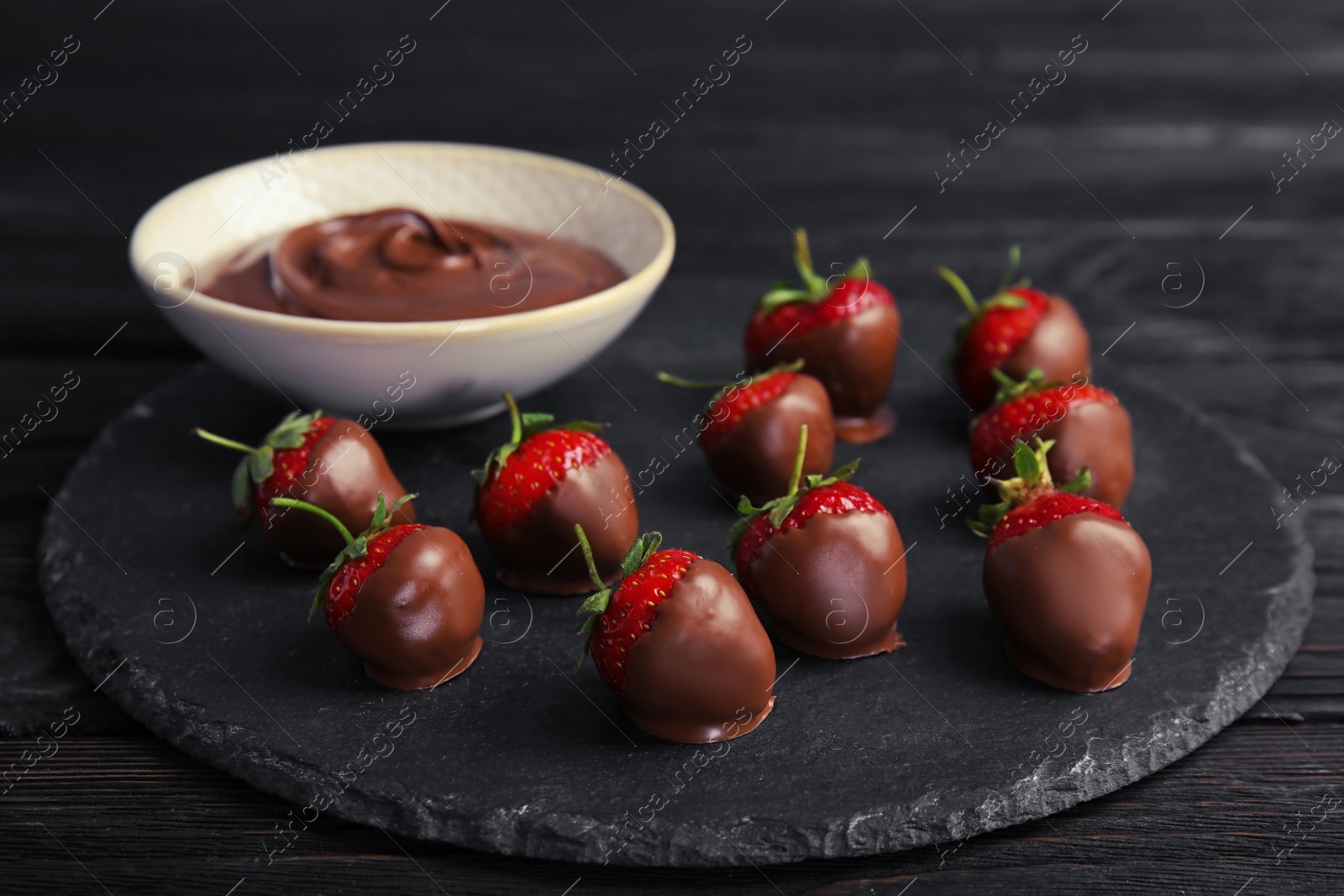 Photo of Slate plate with chocolate covered strawberries on table