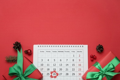 Photo of Flat lay composition with calendar and gifts on red background, space for text. Boxing day concept