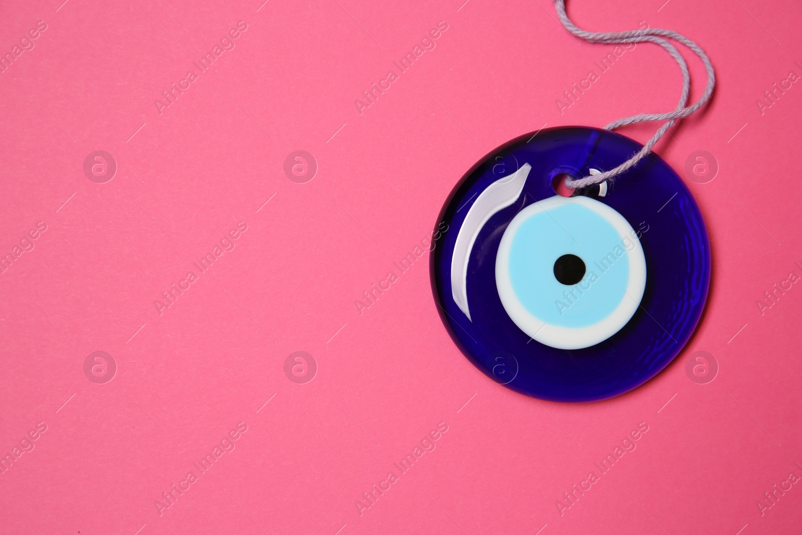 Photo of Evil eye amulet on pink background, top view. Space for text