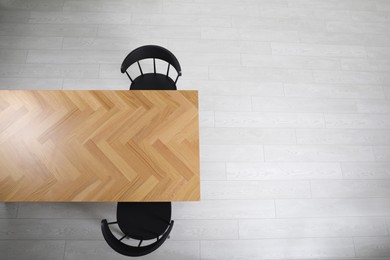 Photo of Wooden table and black chairs indoors, top view. Interior design