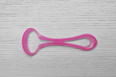 Photo of Pink tongue cleaner on white wooden table, top view