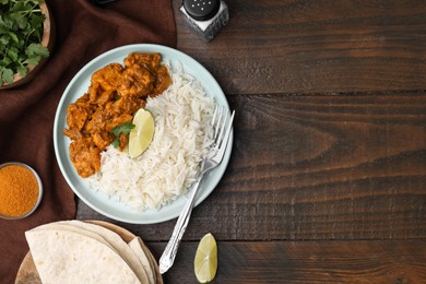 Photo of Delicious chicken curry with rice and ingredients on wooden table, flat lay. Space for text