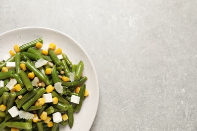 Photo of Delicious salad with green beans, corn and cheese on light table, top view. Space for text