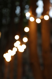 Blurred view of street with garland in evening. Bokeh effect