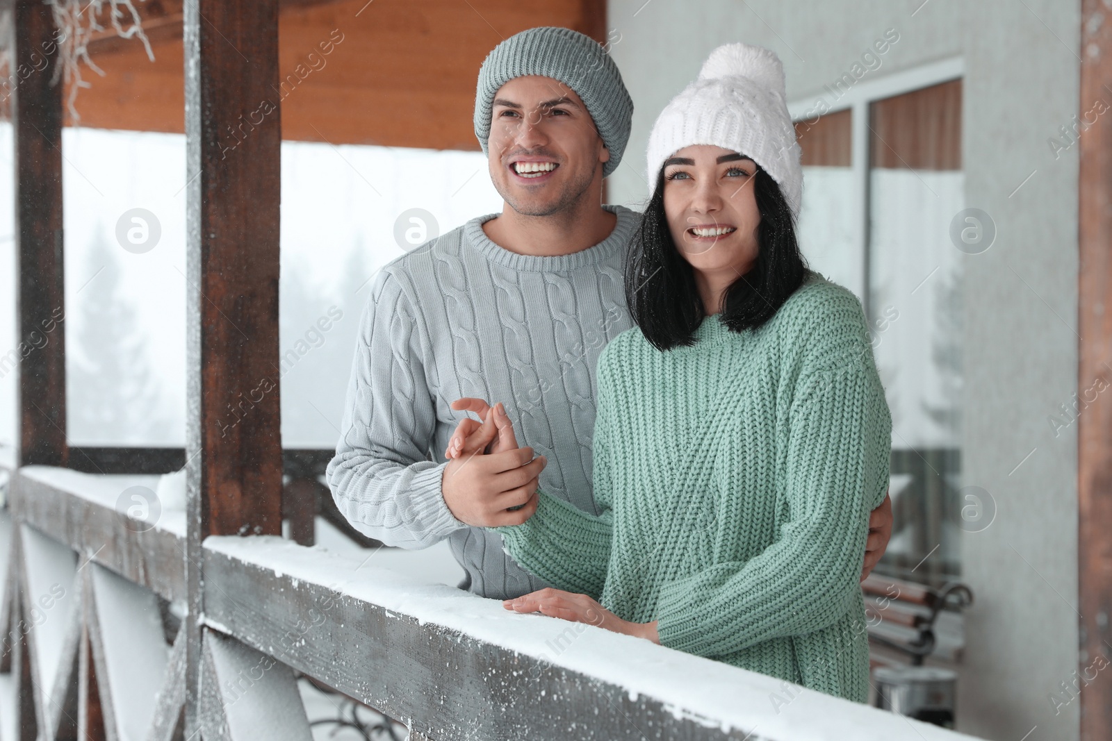 Photo of Lovely couple wearing warm sweaters and hats outdoors on snowy day. Winter season