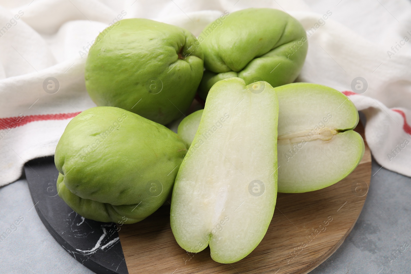 Photo of Cut and whole chayote on gray table, closeup