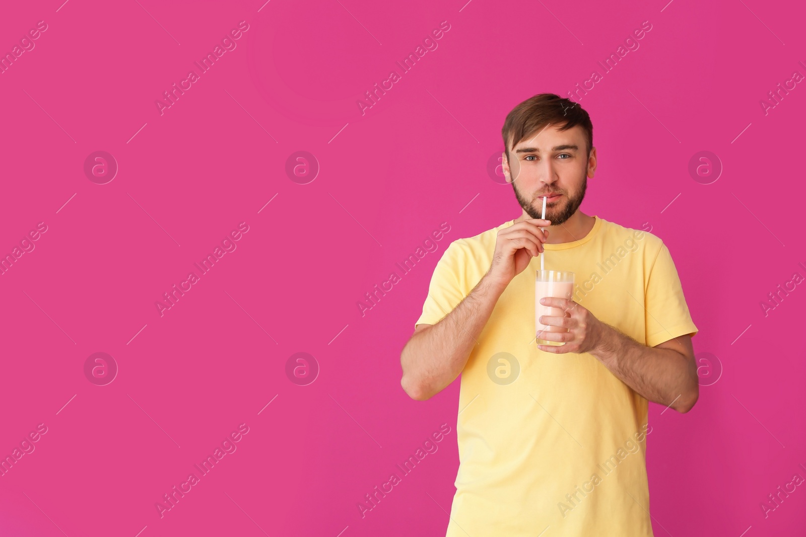 Photo of Young man with glass of delicious milk shake on color background