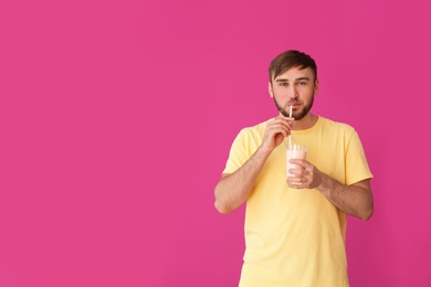 Photo of Young man with glass of delicious milk shake on color background