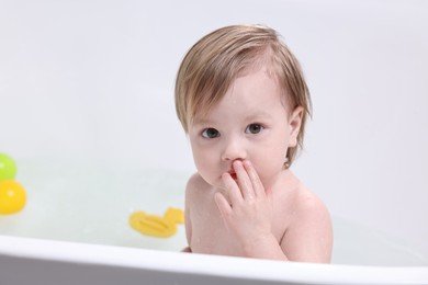 Cute little child bathing in tub at home