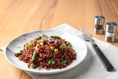 Plate of boiled brown rice with vegetables served on table