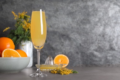 Photo of Glass of Mimosa cocktail on grey table. Space for text