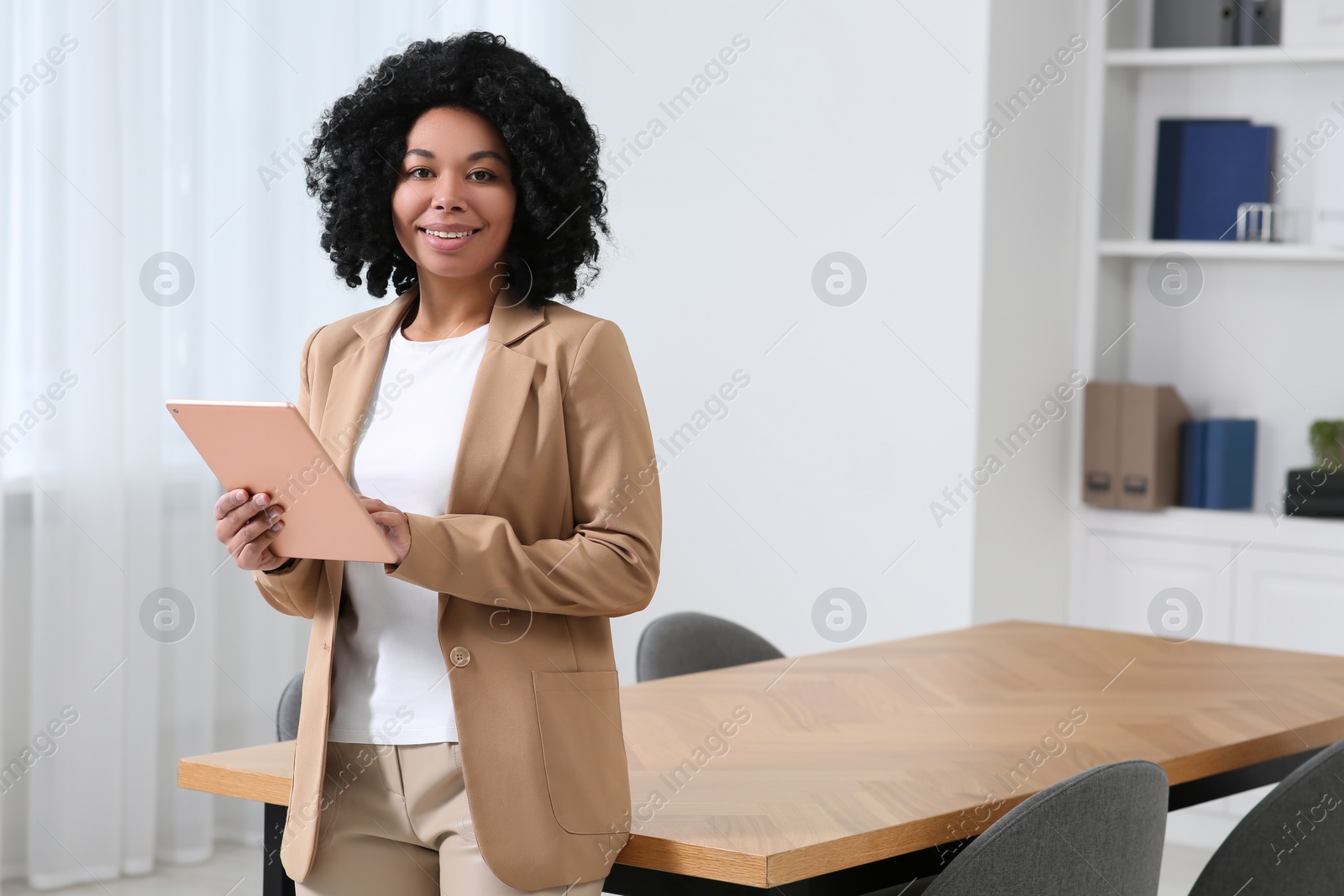 Photo of Smiling young businesswoman using tablet in modern office