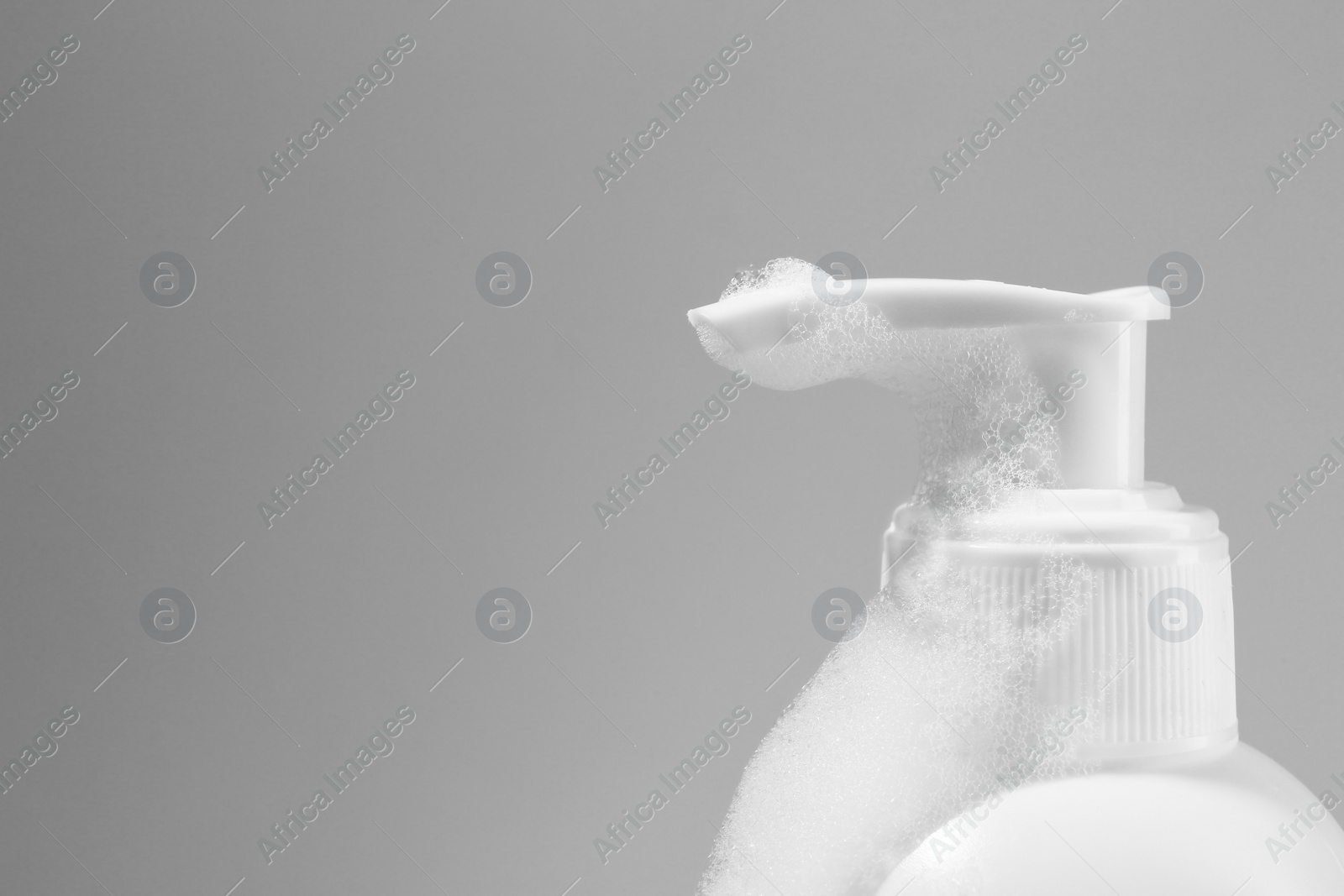 Photo of Dispenser with cleansing foam on light grey background, closeup and space for text. Cosmetic product