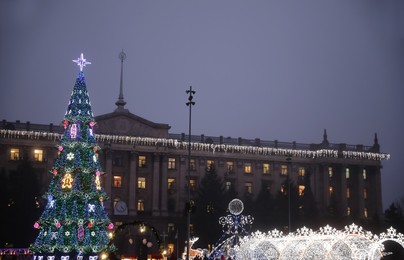 Beautiful decorated Christmas tree near building outdoors in evening