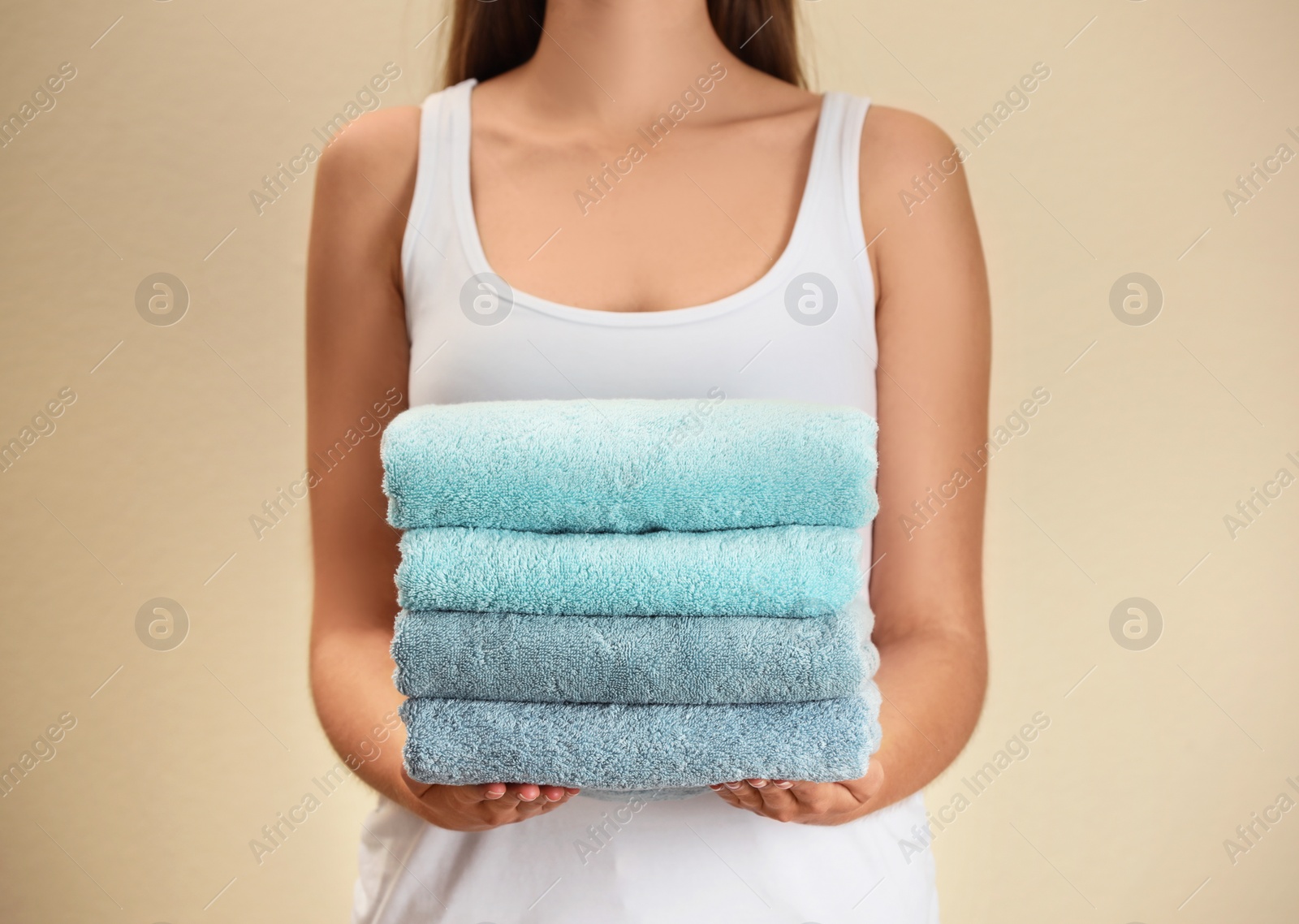 Photo of Woman holding fresh towels on beige background, closeup