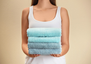 Woman holding fresh towels on beige background, closeup