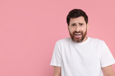 Photo of Portrait of surprised man on pink background, space for text