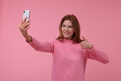 Beautiful woman taking selfie on pink background